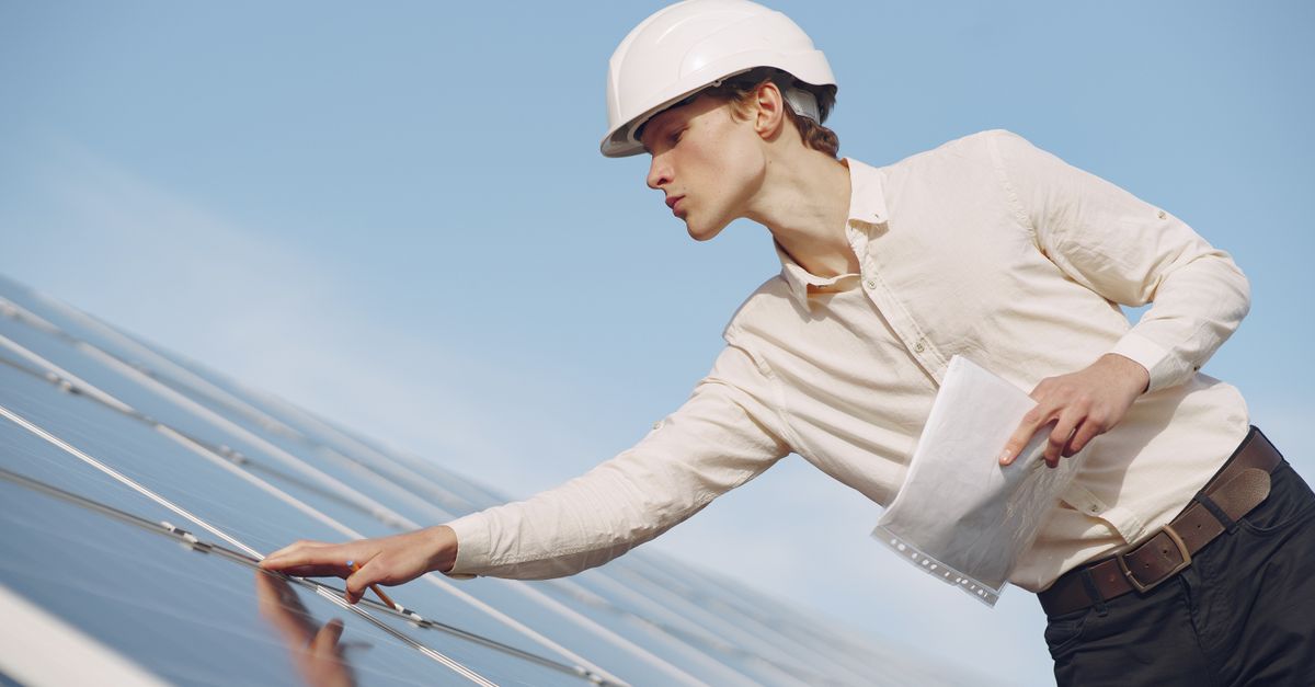 Technicien en casque contrôlant des panneaux photovoltaïques